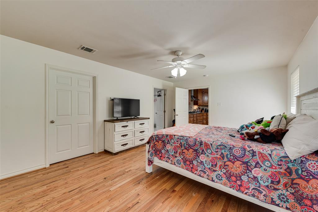 Spacious room featuring wood-finish flooring, a ceiling-mounted fan with integrated lighting, and white six-panel interior doors