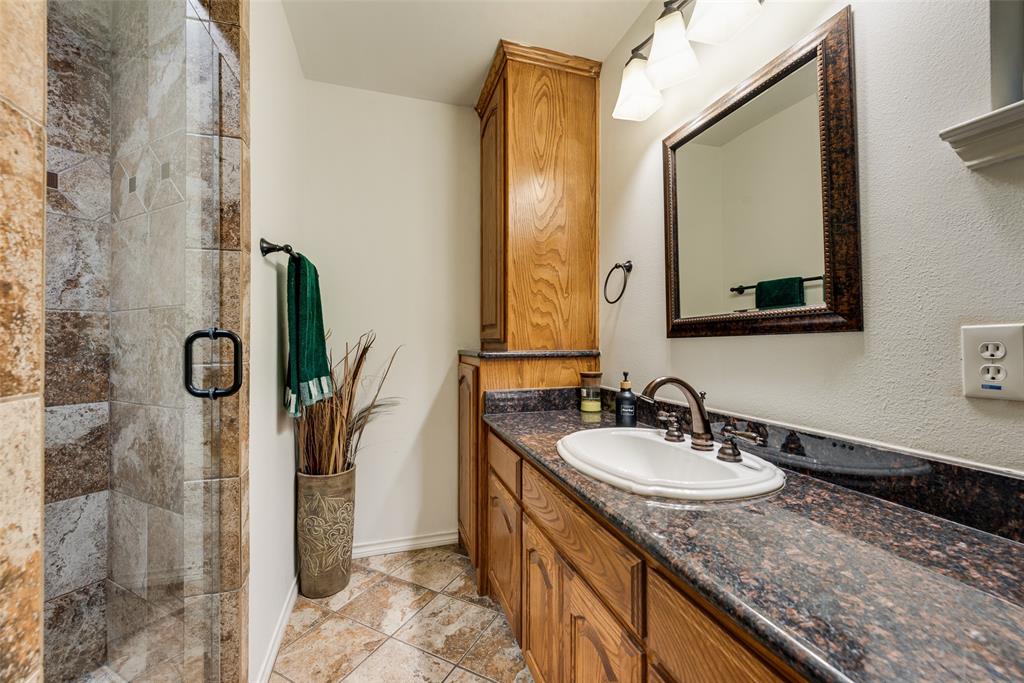 Bathroom featuring a vanity with wood cabinetry, a stone-finish countertop, and a drop-in sink with a multi-handle faucet