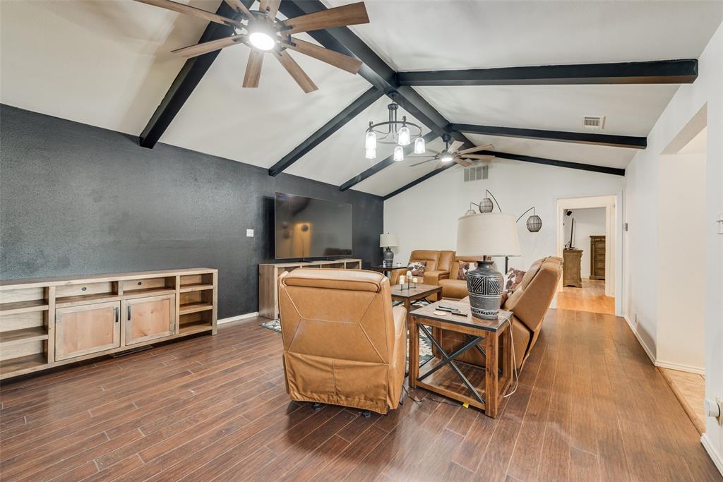 Vaulted ceiling featuring exposed dark-finish structural beams, wood-finish flooring, and dual ceiling fans Vaulted ceiling featuring exposed dark-finish structural beams, wood-finish flooring, and dual ceiling fans