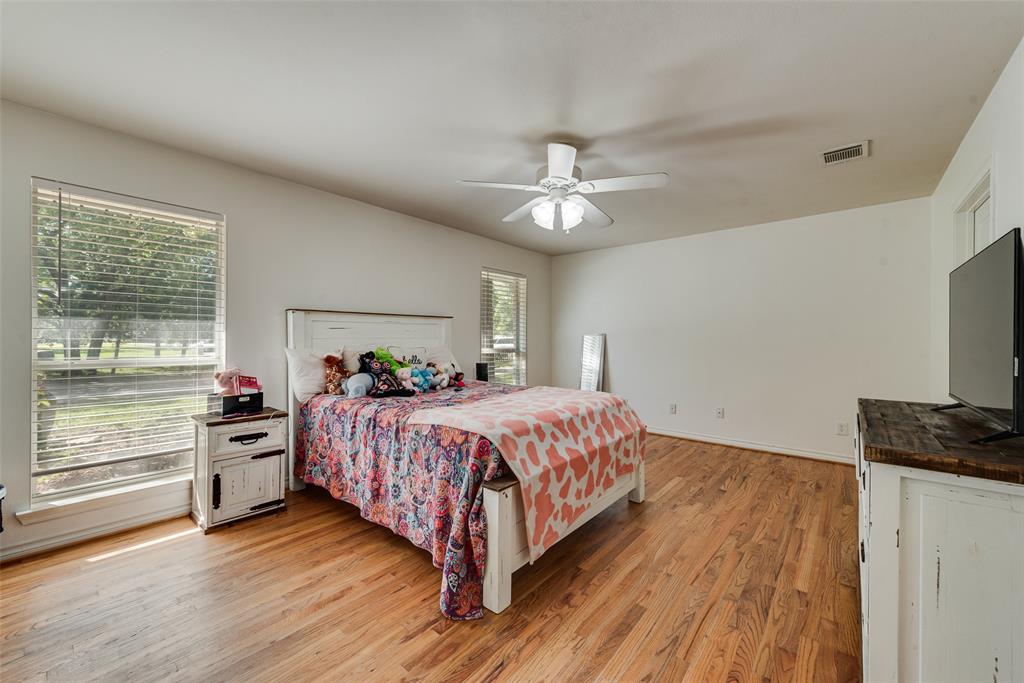 Room featuring wood-finish flooring, dual windows, and a ceiling-mounted light fixture with fan