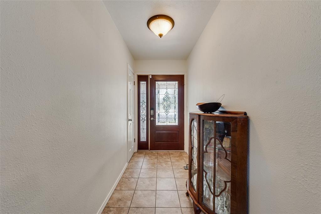 Entryway featuring tile flooring, a stained wood entry door with decorative glass inlay, a matching sidelight, and a flush-mount ceiling fixture Entryway featuring tile flooring, a stained wood entry door with decorative glass inlay, a matching sidelight, and a flush-mount ceiling fixture