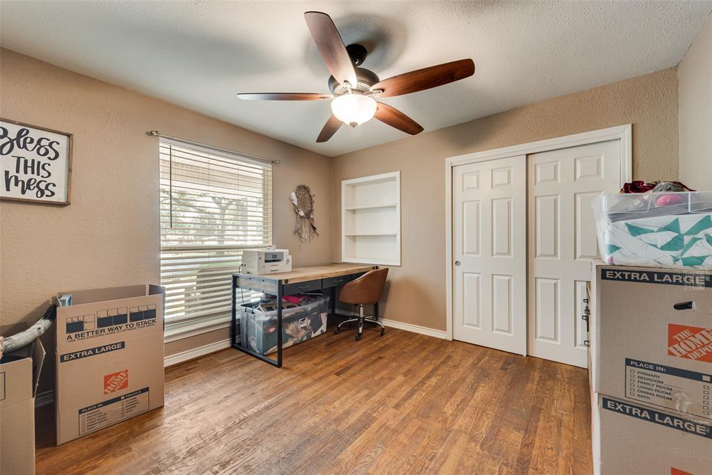 Room featuring wood-finish flooring, a five-blade ceiling fan with integrated light fixture, built-in recessed shelving, and a double-door sliding closet