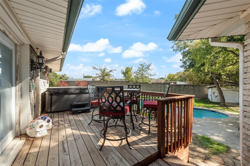 Elevated wood deck featuring a built-in spa, a stone-paved pool area, and a surrounding privacy wall