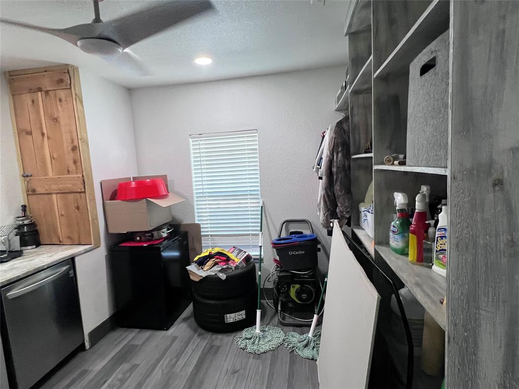 Multi-level wooden shelving, wood-finish flooring, ceiling fan with integrated lighting, and natural wood-toned cabinetry