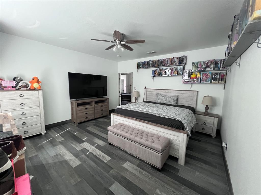 Room featuring wood-finish plank flooring and a multi-blade ceiling fan with integrated lighting
