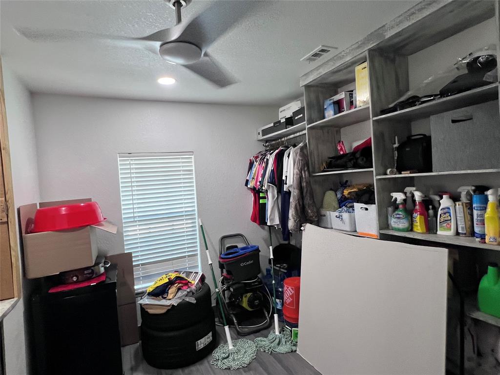 Custom built-in shelving unit, multi-blade ceiling fan, and window with horizontal blinds