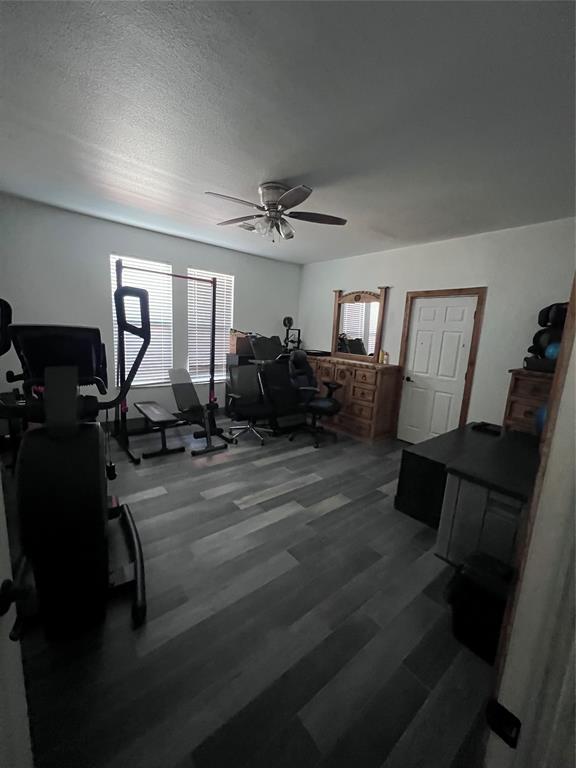 Wood-finish flooring, dual windows with blinds, and ceiling fan with integrated lighting