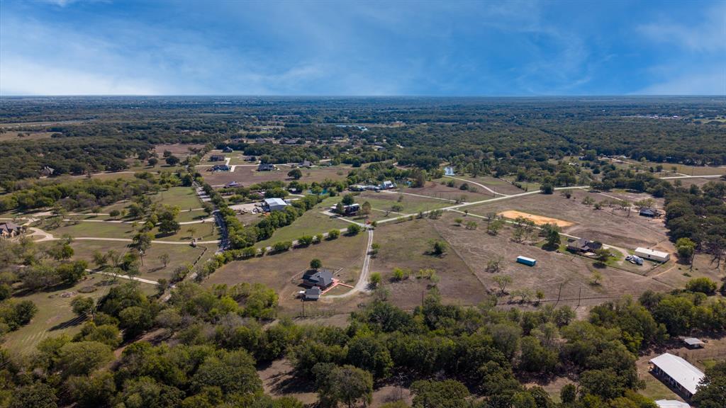 Aerial perspective featuring expansive acreage, mature tree clusters, and established rural road access