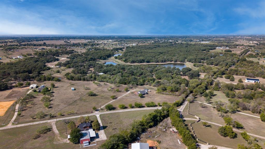 Aerial perspective of rural acreage featuring rolling pastures, dense tree lines, and multiple water features