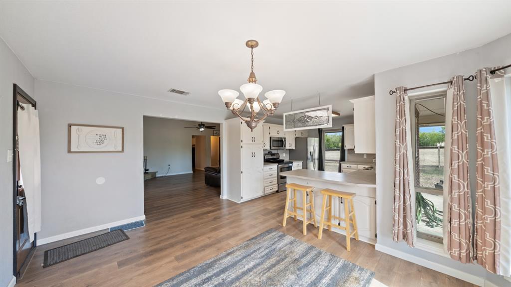 Kitchen area featuring white cabinetry, a breakfast bar, wood-finish flooring, and a multi-arm chandelier