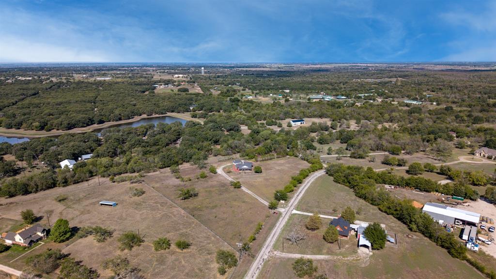 Aerial view of extensive acreage featuring mature trees, open pastureland, and a natural pond