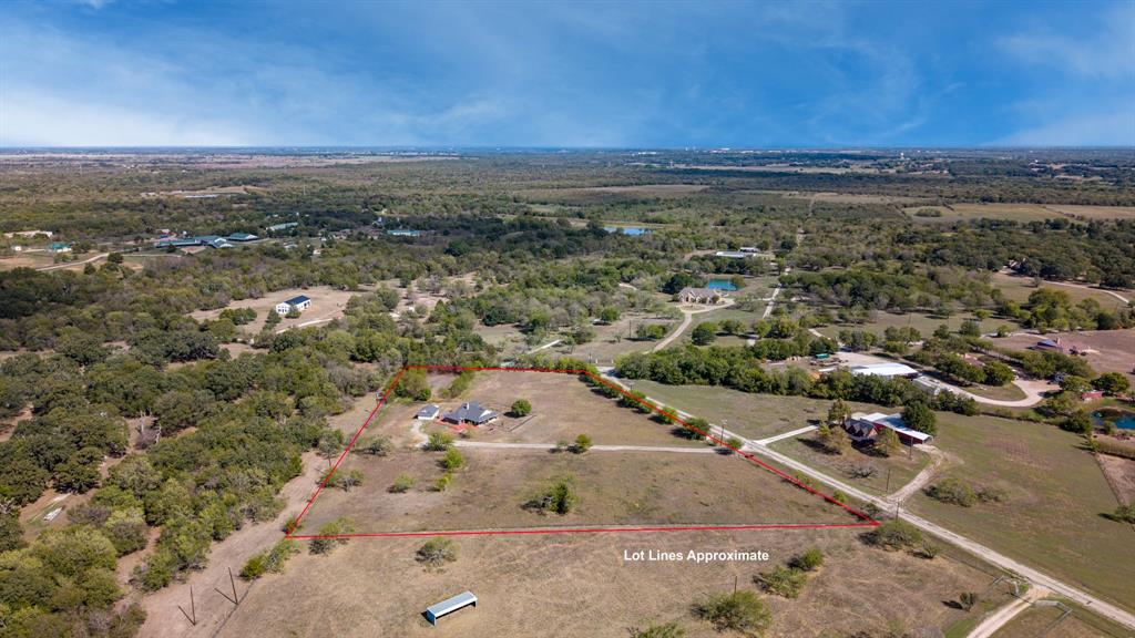 Expansive acreage featuring mature trees, open pasture, and a gravel driveway
