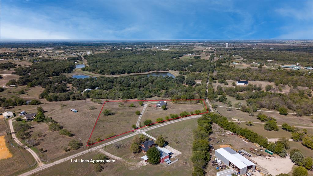 Expansive acreage featuring cleared land, mature trees, a long gravel driveway, and a fenced perimeter