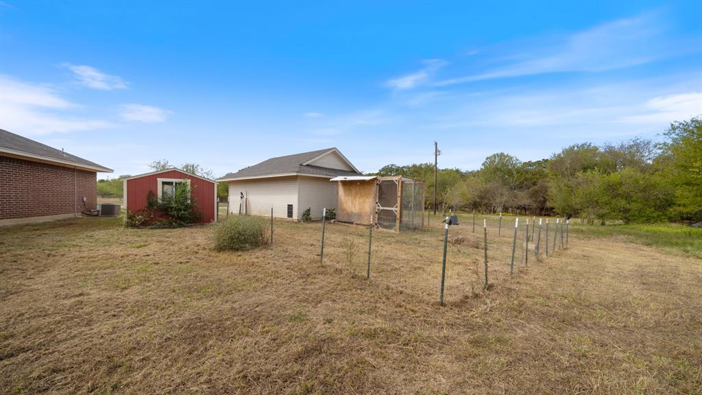 Expansive yard featuring a red storage structure, detached garage, and fenced enclosure