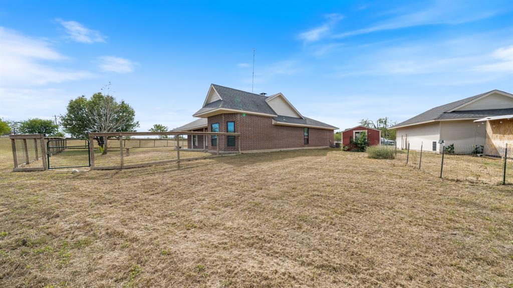 Brick exterior home featuring a fenced outdoor perimeter, gable rooflines, and an accessory storage structure