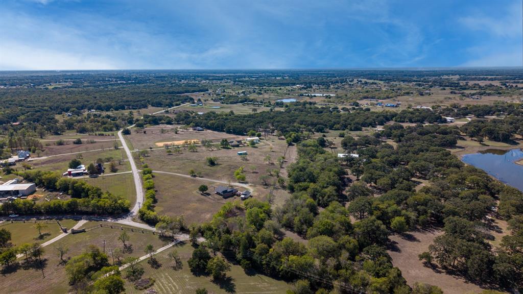 Expansive acreage featuring mature tree clusters, open pasture land, and a natural body of water