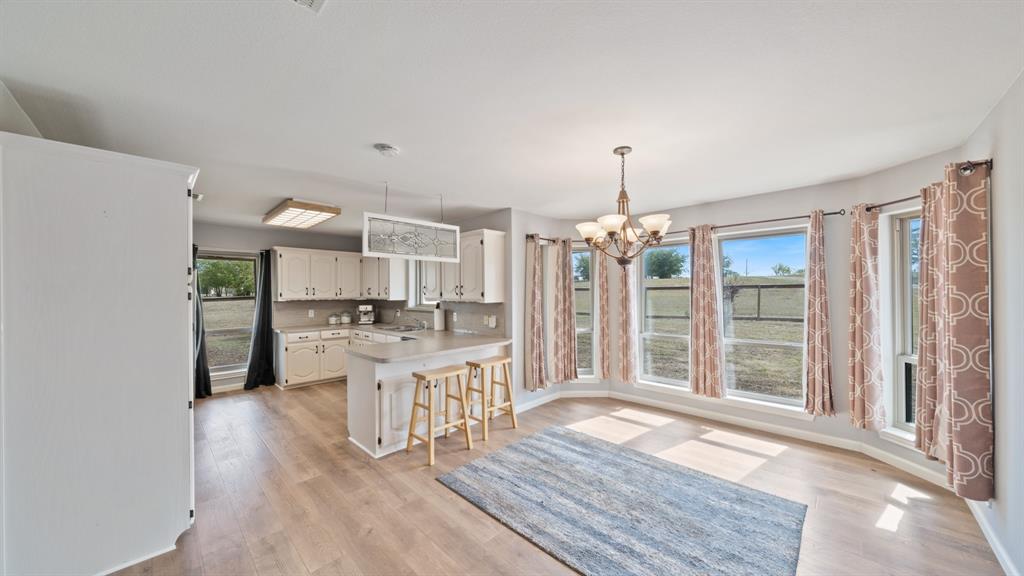 Kitchen featuring white cabinetry, wood-finish flooring, a breakfast bar, and large windows providing natural light
