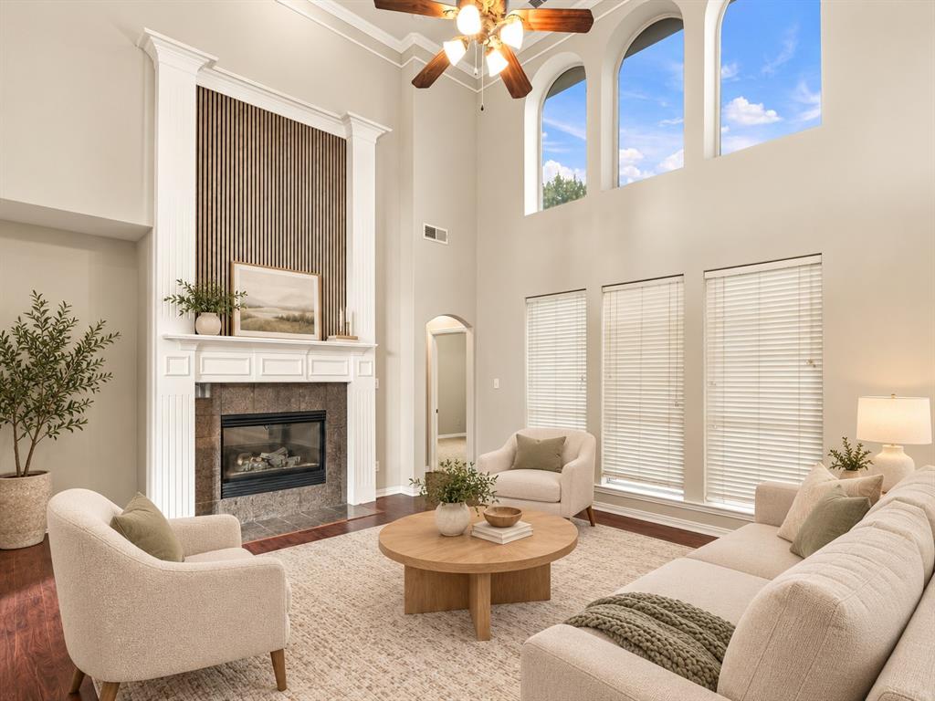 Double-height ceiling, floor-to-ceiling fireplace with wood-slat detailing, arched clerestory windows, and wood-finish flooring