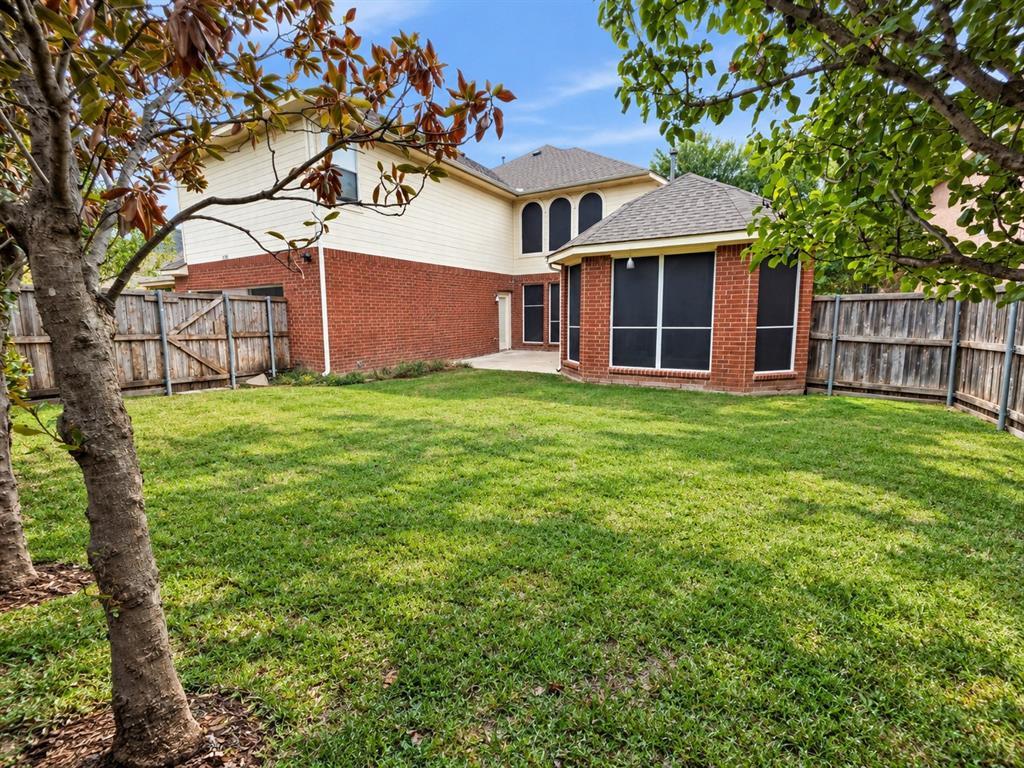 Backyard featuring a grass lawn, perimeter wood fencing, masonry and siding exterior, multi-pane windows with screens, and a concrete patio