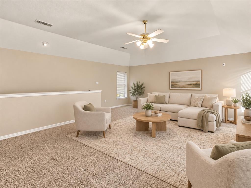 Vaulted ceiling featuring a central multi-blade ceiling fan with integrated light fixture and neutral wall-to-wall carpeting