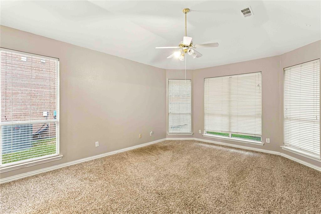 Room featuring neutral wall tones, wall-to-wall carpeting, multiple windows with fitted blinds, and a ceiling-mounted light fixture with fan