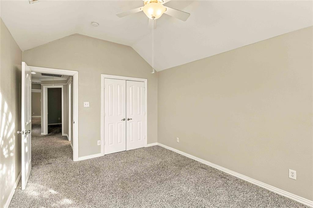 Vaulted ceilings featuring a central ceiling fan, neutral wall finishes, and double-door closet cabinetry