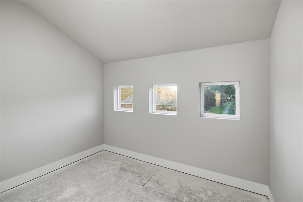 Vaulted ceiling room featuring three inset square windows and concrete flooring