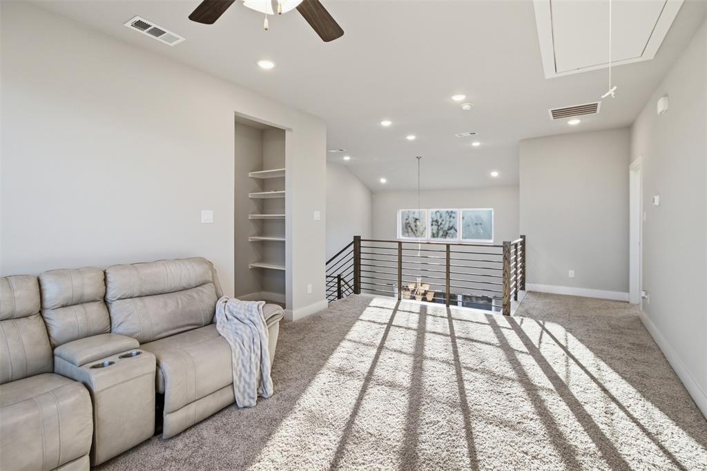 Vaulted ceilings, recessed lighting, horizontal metal-railing overlook, built-in shelving, and neutral wall-to-wall carpeting