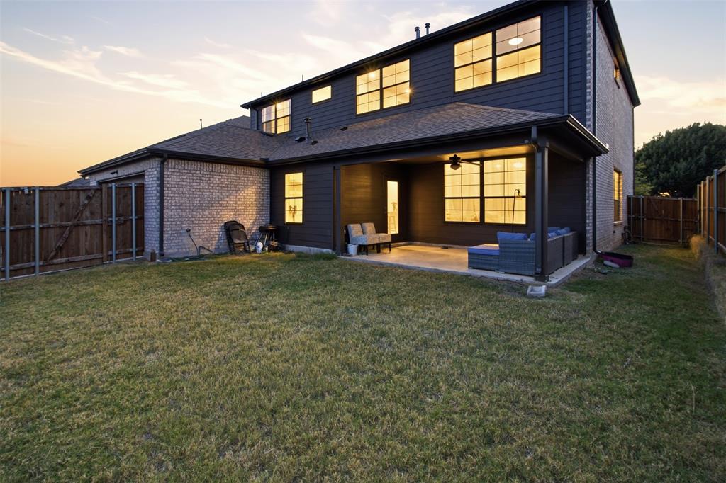 Two-story exterior featuring a combination of brick and horizontal siding, a covered rear patio, a fenced backyard, and multi-pane windows