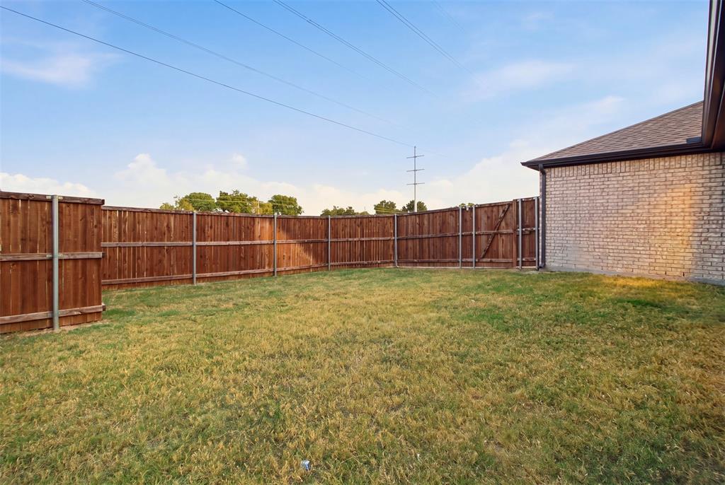 Backyard featuring a grass lawn, full-perimeter wood privacy fencing, and masonry exterior wall construction