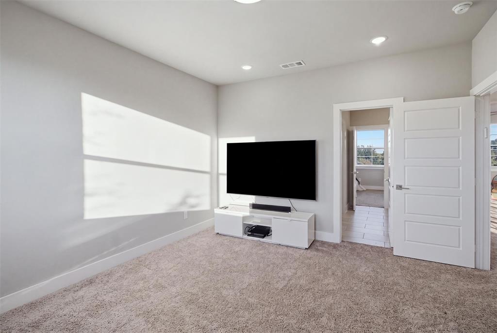 Neutral-toned interior space featuring recessed ceiling lighting, wall-to-wall carpeting, and a four-panel interior door
