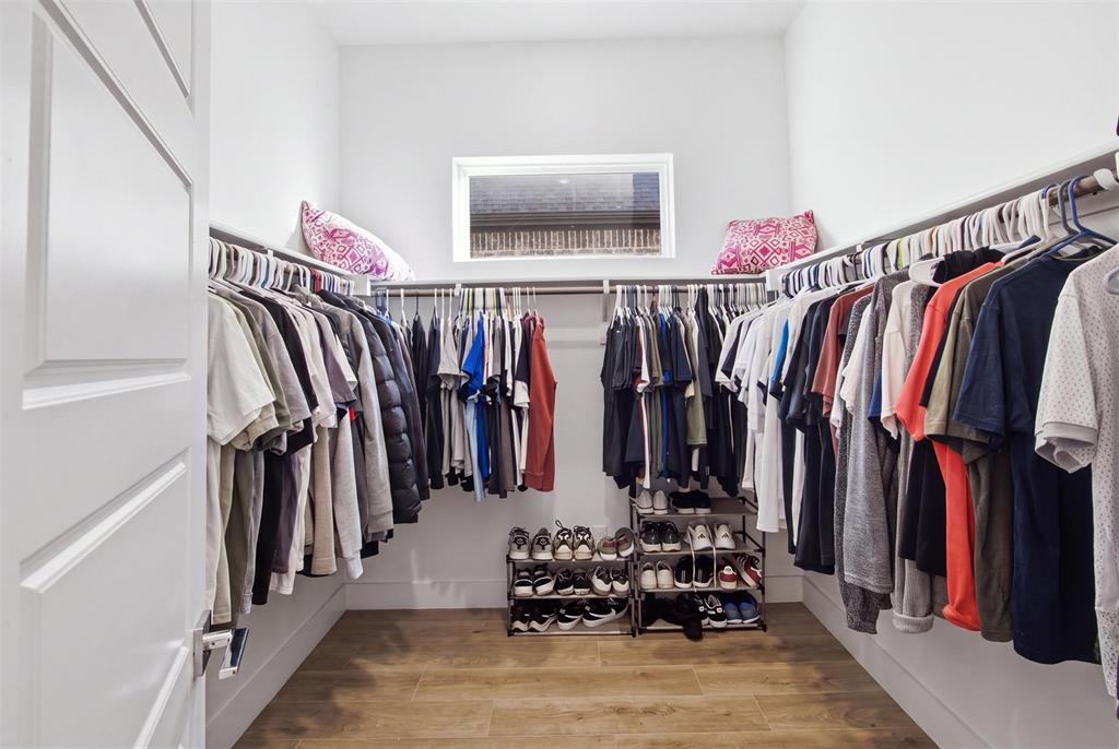 Walk-in closet featuring wood-finish flooring, built-in metal shelving, and a horizontal window