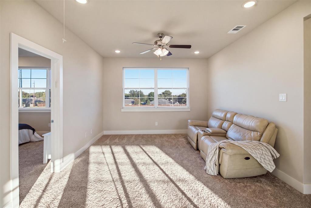 Neutral-toned carpeted interior featuring recessed lighting, a ceiling fan with integrated light fixture, and windows with white muntins