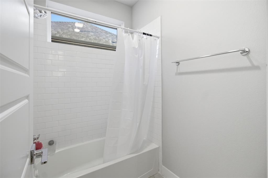 Tub and shower combination featuring white subway tile surround, high-set horizontal window, and polished chrome hardware