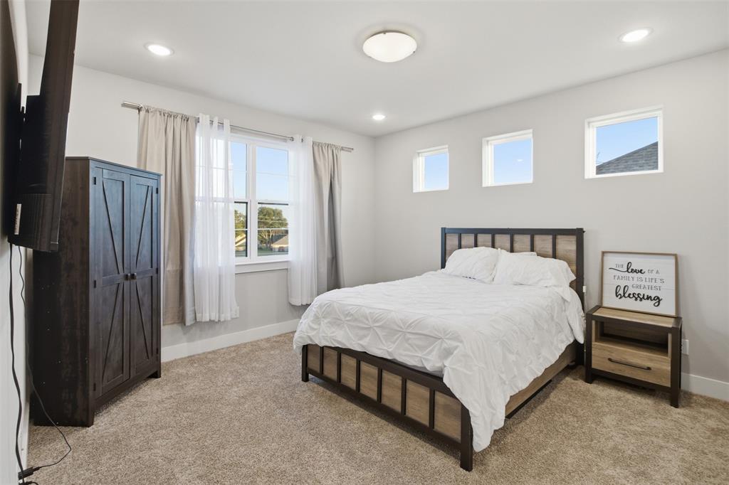 Neutral-toned interior featuring wall-to-wall carpeting, recessed ceiling lighting, a large double-hung window, and three high-set square windows
