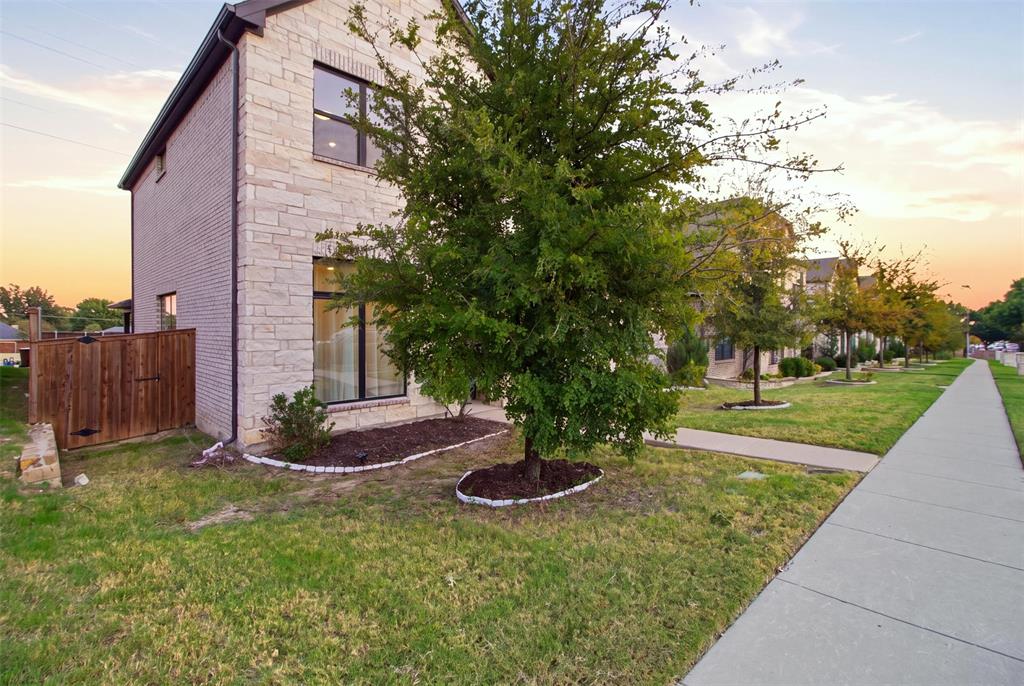 Exterior featuring light-toned stone masonry, dark-framed windows, and a wood privacy fence