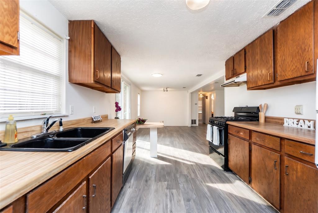 Kitchen featuring wood cabinetry, laminate countertops, double-basin sink, and wood-finish flooring Kitchen featuring wood cabinetry, laminate countertops, double-basin sink, and wood-finish flooring
