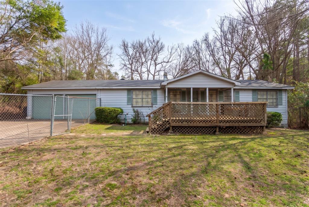 Single-story residence featuring lap siding, a wooden front deck with lattice skirting, an attached two-car garage, and a chain-link fenced perimeter Single-story residence featuring lap siding, a wooden front deck with lattice skirting, an attached two-car garage, and a chain-link fenced perimeter