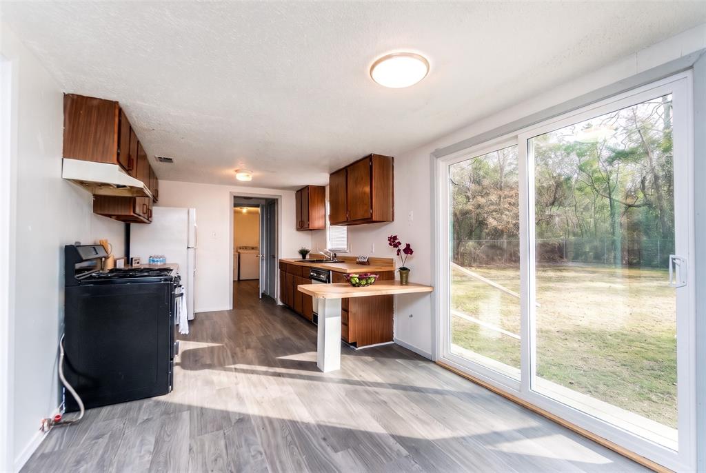 Kitchen featuring wood-finish cabinetry, built-in breakfast bar, wood-finish flooring, and sliding glass doors with exterior yard access Kitchen featuring wood-finish cabinetry, built-in breakfast bar, wood-finish flooring, and sliding glass doors with exterior yard access