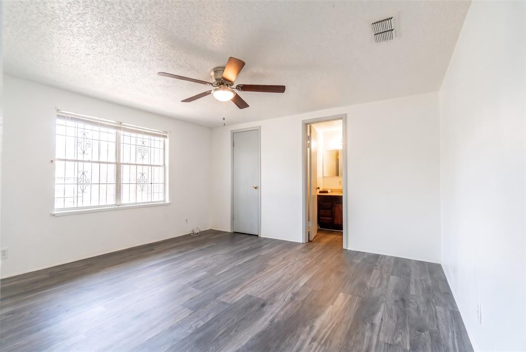 Wood-finish flooring, ceiling fan with integrated lighting, and window featuring decorative metal security bars