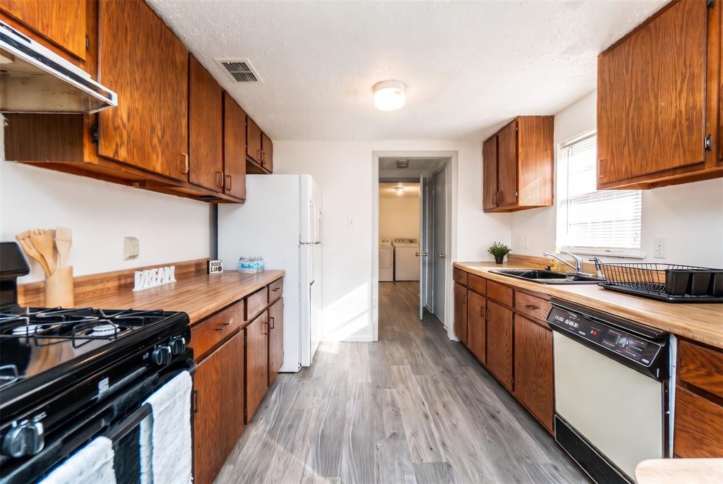Kitchen featuring wood cabinetry, butcher block-style countertops, wood-finish flooring, and a stainless steel gas range Kitchen featuring wood cabinetry, butcher block-style countertops, wood-finish flooring, and a stainless steel gas range