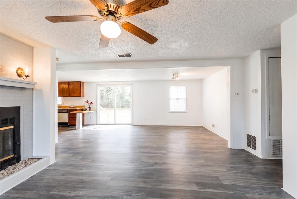 Painted brick fireplace, wood-finish flooring, ceiling fan, sliding glass door, and recessed lighting Painted brick fireplace, wood-finish flooring, ceiling fan, sliding glass door, and recessed lighting