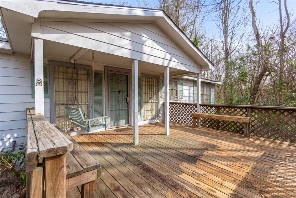 Covered front porch featuring wood decking, built-in wooden benches, and a gable roofline