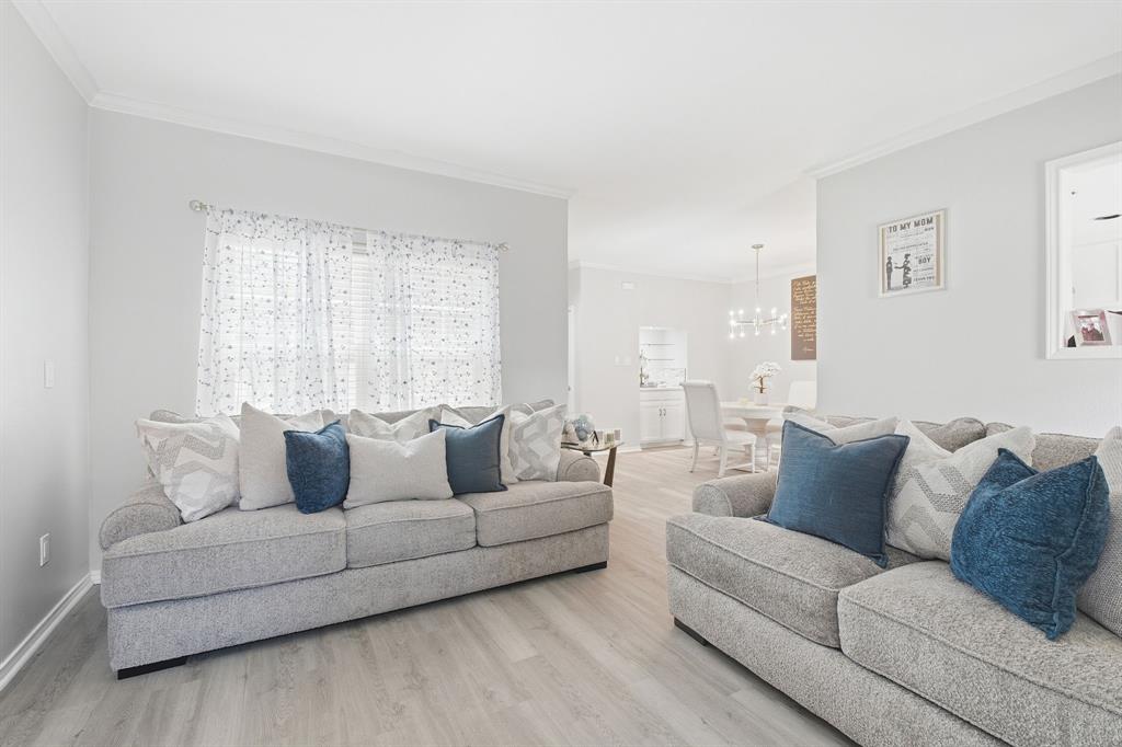 Neutral-toned interior featuring wood-finish flooring, crown molding, and a multi-light chandelier fixture Neutral-toned interior featuring wood-finish flooring, crown molding, and a multi-light chandelier fixture