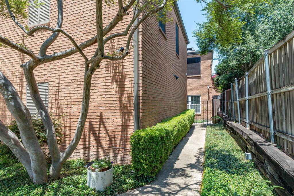 Brick exterior finish featuring a concrete walkway, trimmed shrubbery, and wood fencing Brick exterior finish featuring a concrete walkway, trimmed shrubbery, and wood fencing