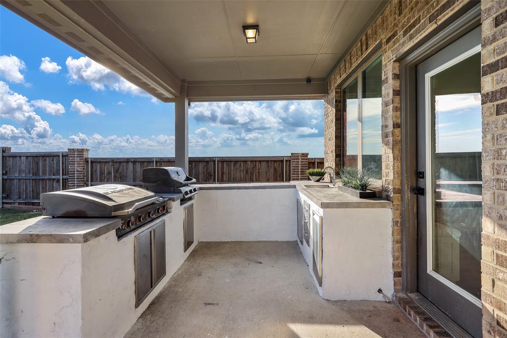 Covered outdoor kitchen with Blackstone, built in grill, sink & ample storage SS cabinets