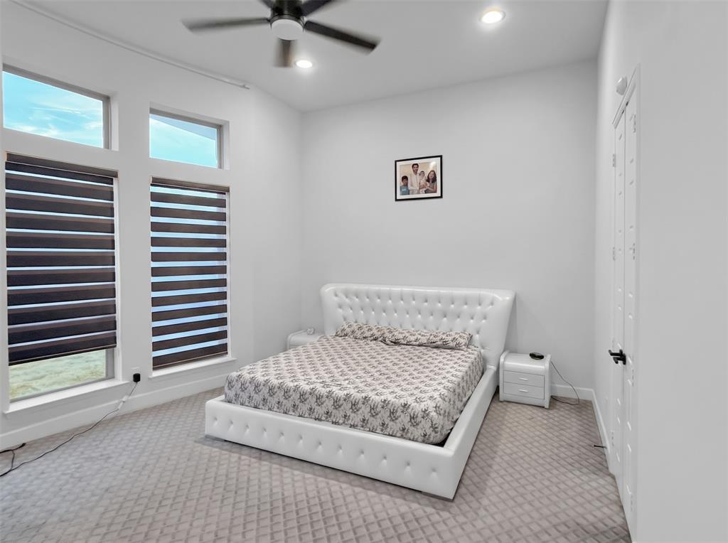 High-ceiling room featuring neutral carpeting, dual-pane windows with adjustable roller shades, recessed lighting, and a multi-speed ceiling fan