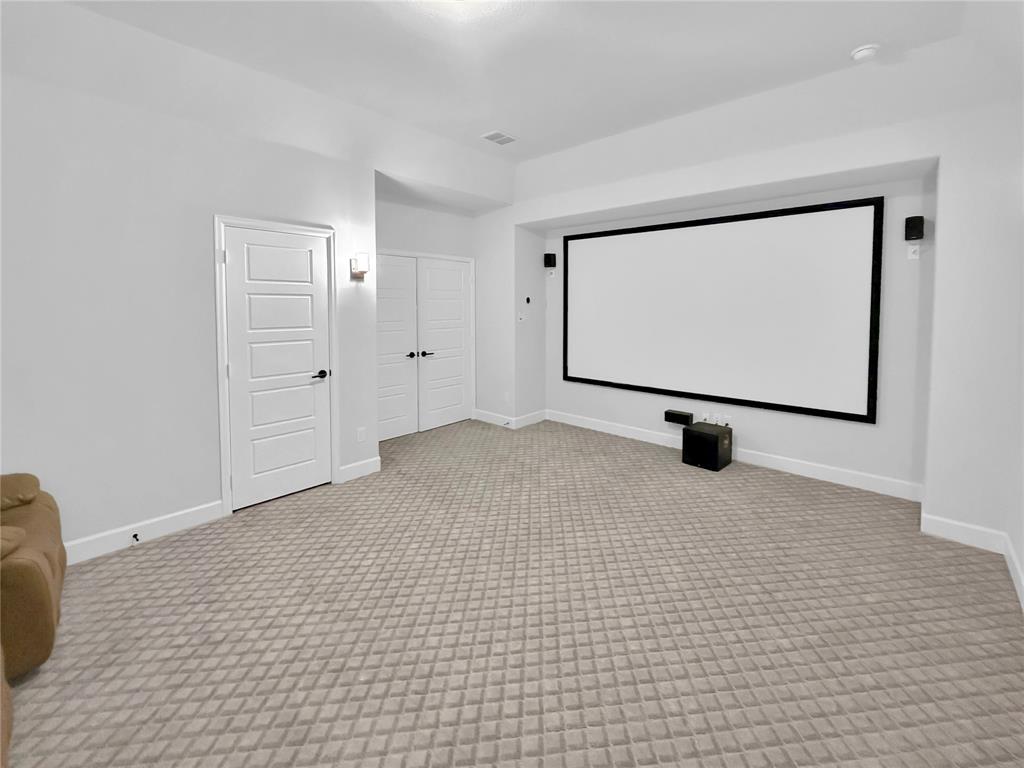 Media room featuring a built-in projector screen, wall-mounted speakers, recessed lighting, and patterned wall-to-wall carpeting