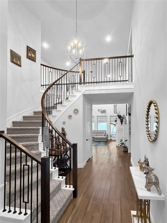 Grand foyer featuring a sweeping curved staircase with iron balusters and a wood handrail, polished wood-finish flooring, and a multi-light contemporary orb pendant fixture