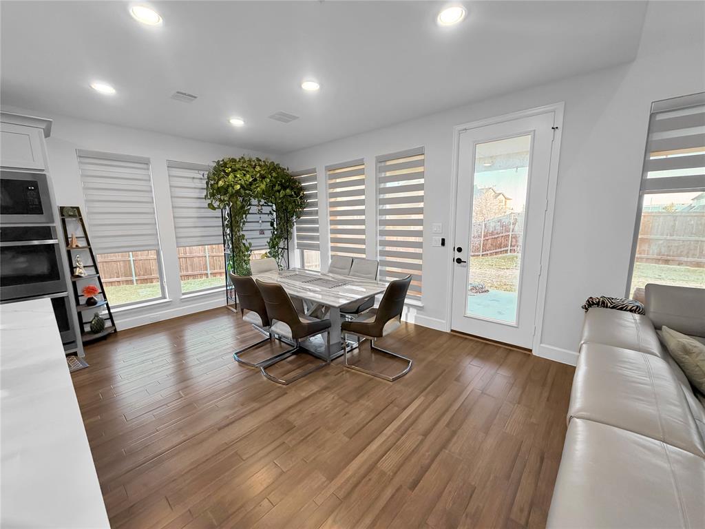 Wood-finish flooring, recessed lighting, multiple oversized windows with integrated shades, and a glass-paneled exterior door